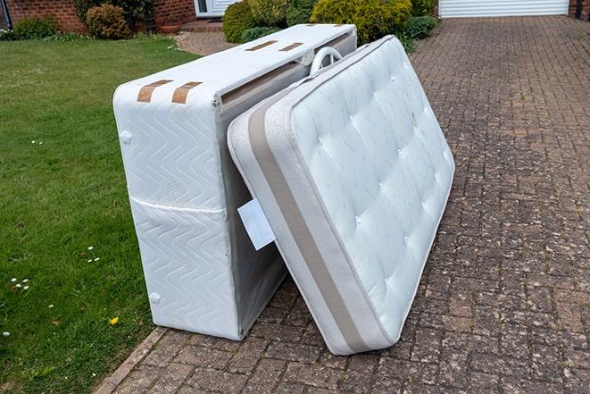 two workers hauling away an old mattress